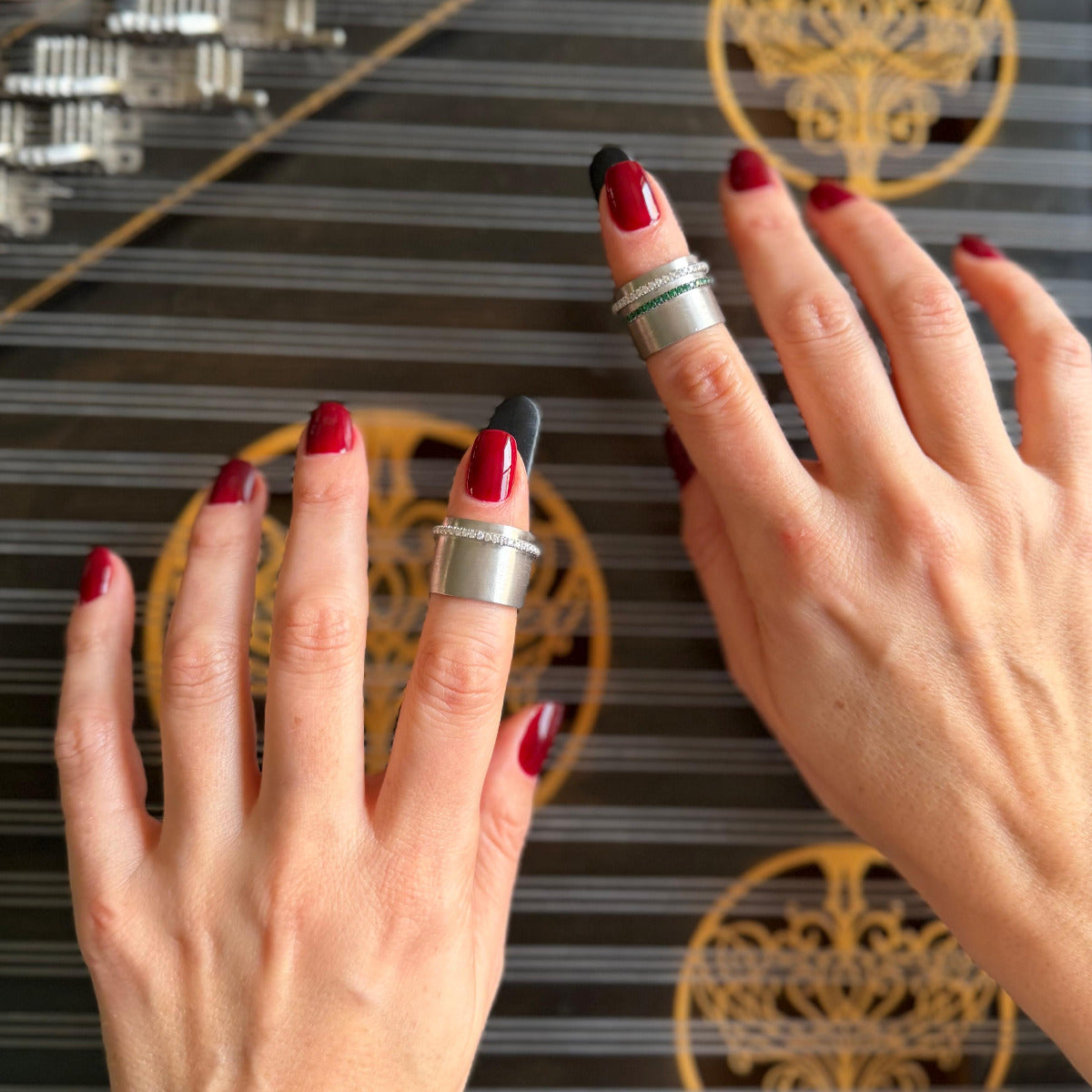 Close-up of two hands with red nail polish and white gold rings playing qanun.