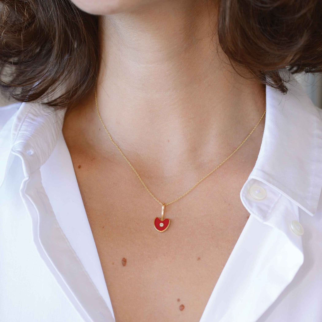 red heart shape gold pendant with diamond on a woman